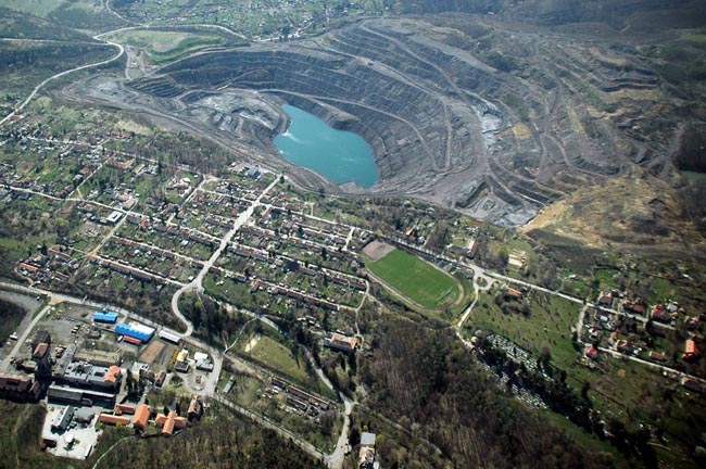 Ugyan nem önálló település, de jellegzetes bányásztelep (kolónia) szabályos utcákkal és egyenházakkal, egy mélyművelésű aknával (lent) és egy 2004-ben felhagyott külszíni fejtéssel. (Pécsbányatelep, Pécs, Trócsányi A. felvétele)